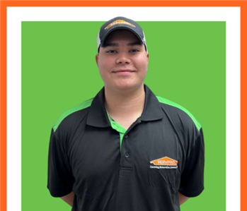 SERVPRO employee in front of green wall