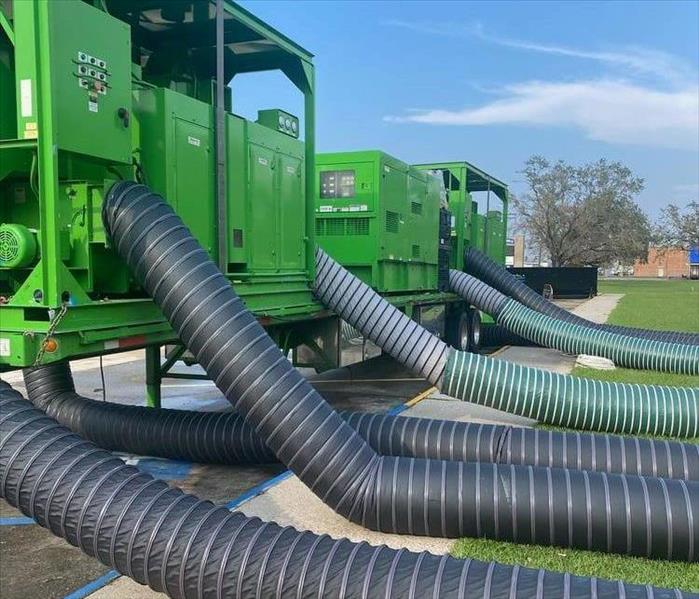 Water damage restoration equipment; bright green trailers and large hoses